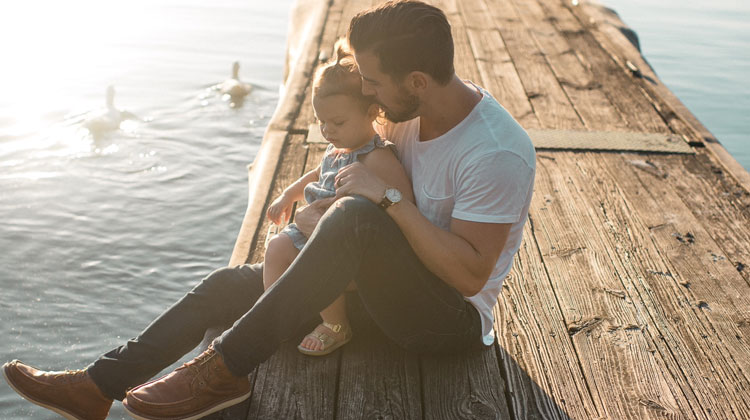father holding daughter on bridge