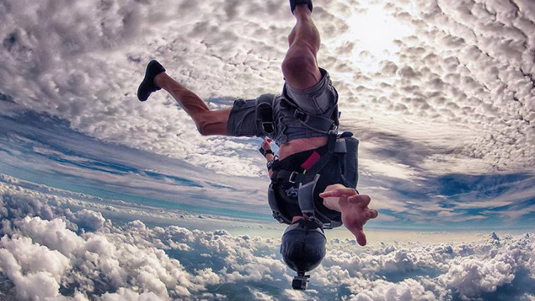 Guy skydiving upside down in clouds