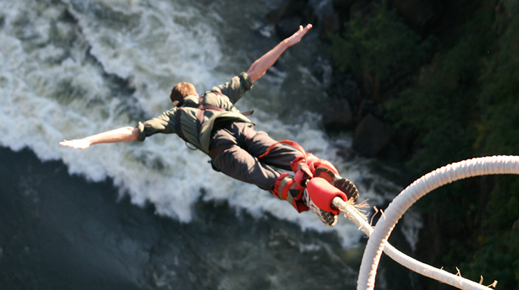 Man bungee jumping over huge cliff