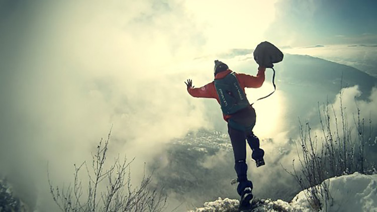 man jumping off of cliff before beginning base jump