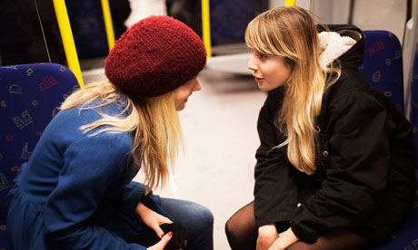 Two teenage girls talking on subway train