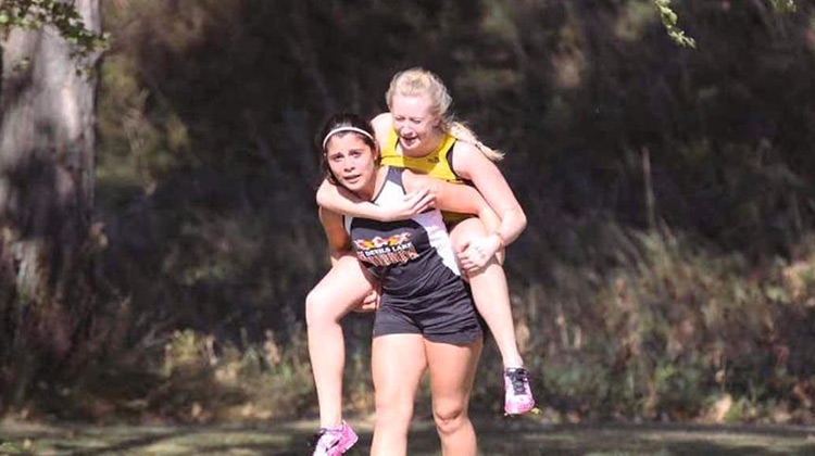 Runner Melanie Bailey carrying competitor Danielle LeNou on her back.