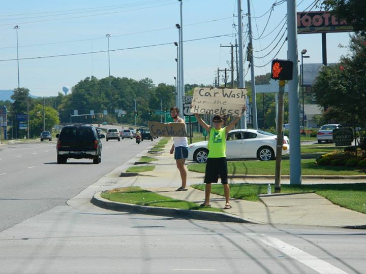 two frat members hold signs for car wash 