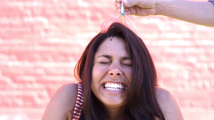 Girl reacting to whisk-like head massage tool in slow motion