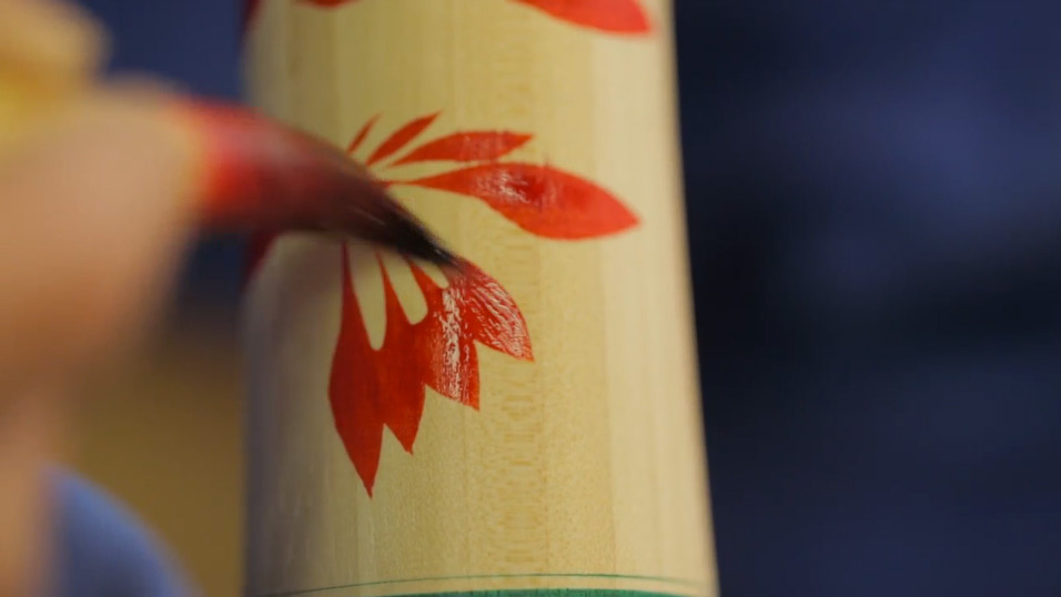 Painting the chrysanthemum pattern onto the body of the doll.