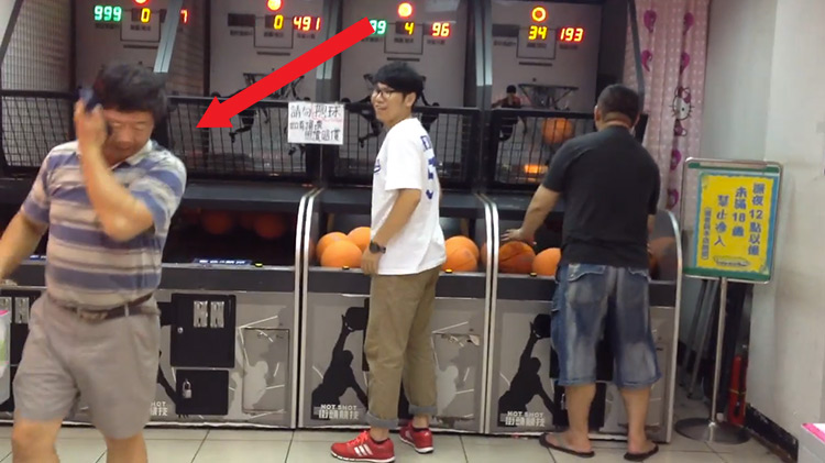 Old asian man walking away from arcade basketball game