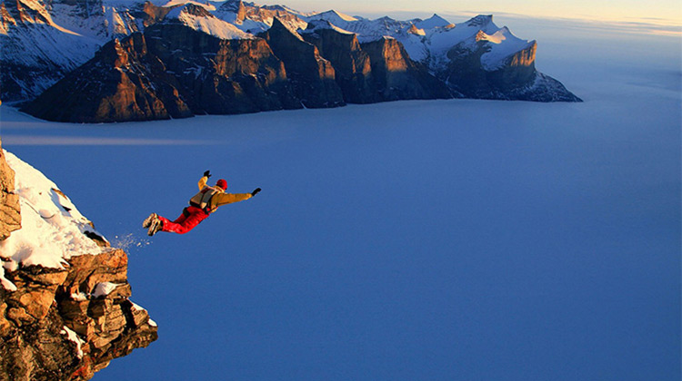 Man base jumping off cliff into the clouds