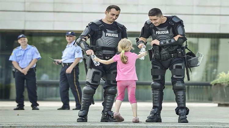 Little girl handing riot officers water