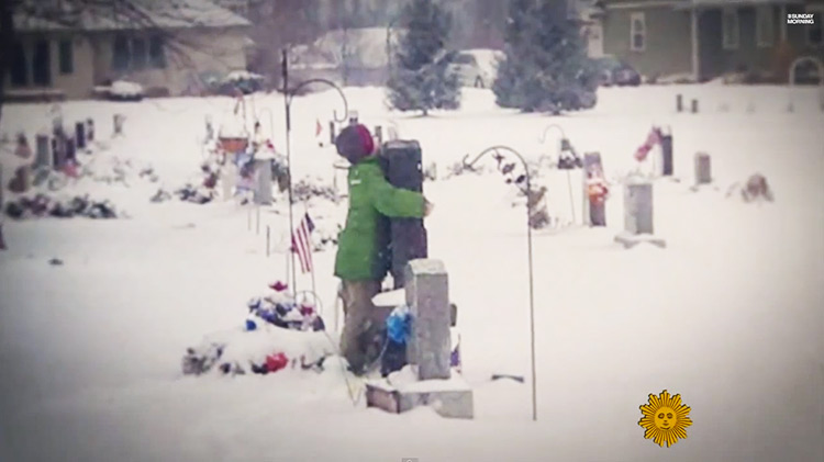 Myles Eckhert hugging his father's grave stone