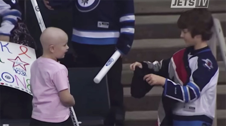 Boy handing girl a hockey stick at game