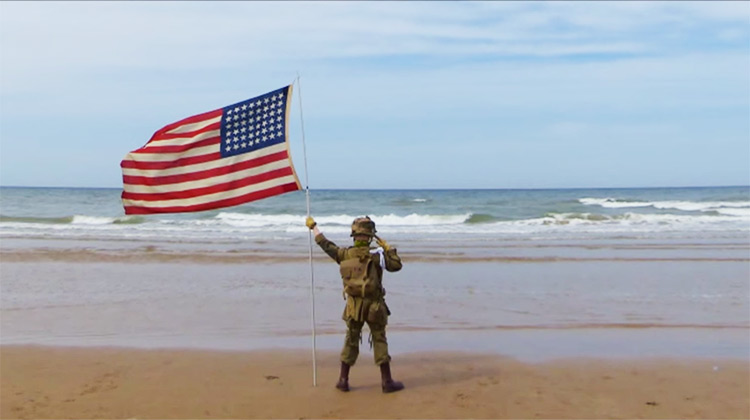 Boy saluting with flag on Omaha beach