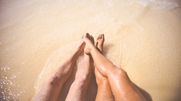 Couple's legs in water at beach