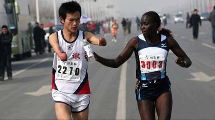 Marathon runner handing water bottle to armless runner