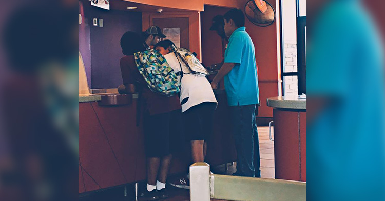 Back view of teens standing at a Taco Bell counter ordering food.