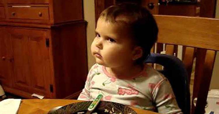 Toddler Veronica deep in thought as she sits at the dining room table.