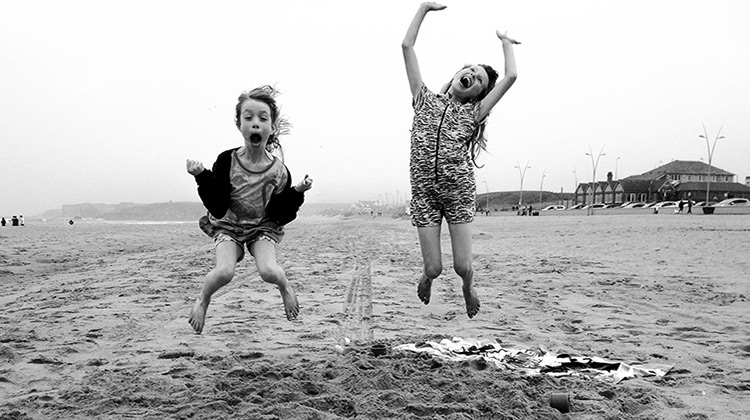 Two girls jumping and smiling on the beach
