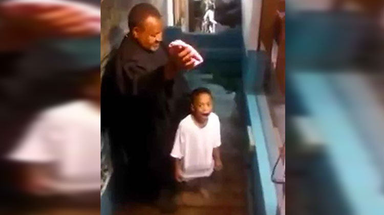 LITTLE BOY WITH excited face about to be baptized in water