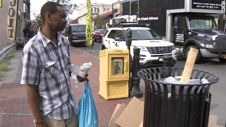 homeless man looking at trash can