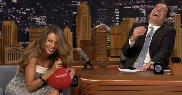 sofia vergara and jimmy fallon laughing. vergara is holding a balloon.