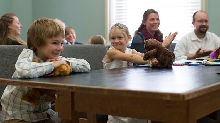 little kids holding stuffed animals smile