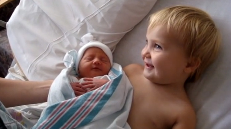 little girl holding baby sister for first time