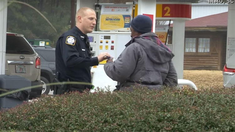 Police officer handing homeless man giftcard