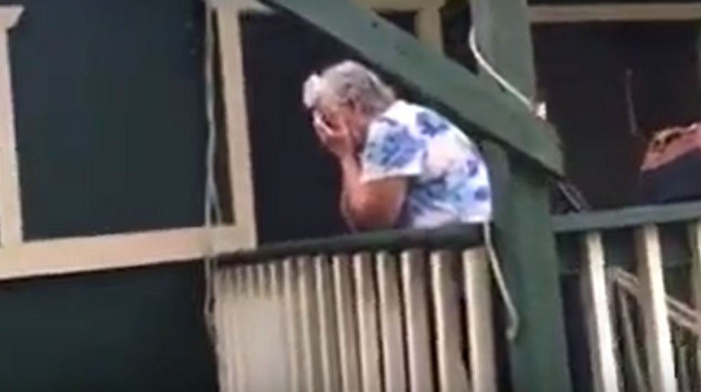 grandma hunched over crying in front of green house.