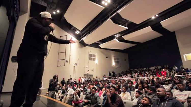 Eric Thomas addressing high school students at an auditorium.