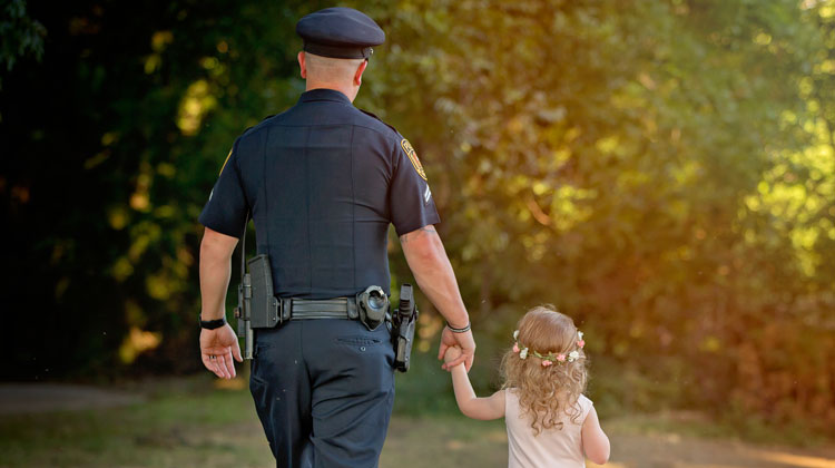 cop holding hand of little girl in pink dress