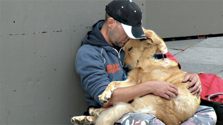 homeless man holding large dog in lap