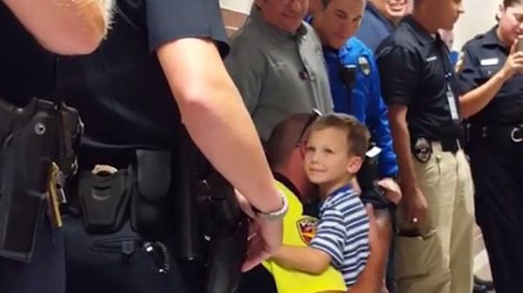 little boy in blue hugged by cops