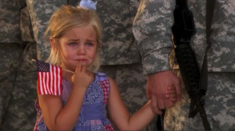 little girl crying holding military man's hand