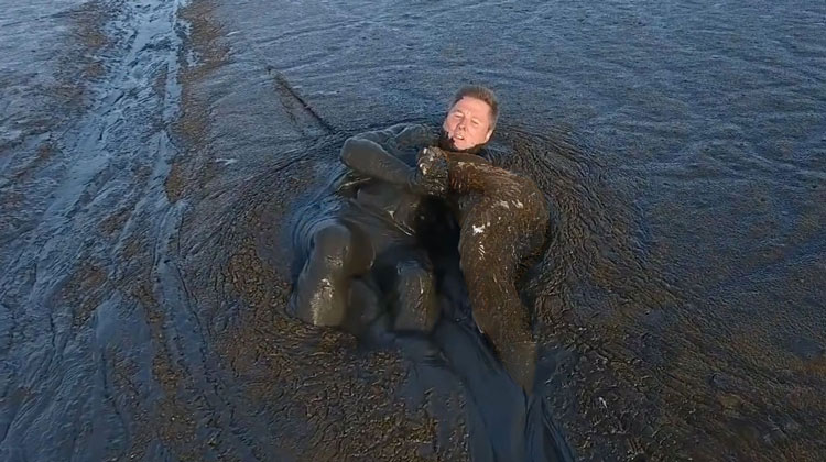 man in swamp holding drenched animal