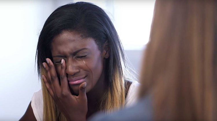 teenager cries, wiping tears from face