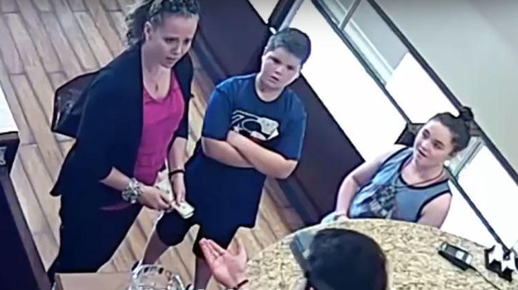 mother stunned holding cash as jeweler reaches hand out