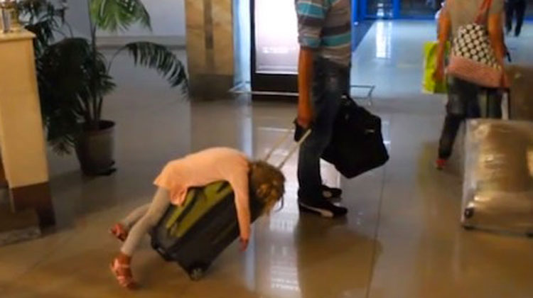 kid fell asleep on suitcase while dad rolls it out of hotel