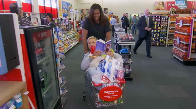 ellen reading book in shopping cart and michelle obama pushing