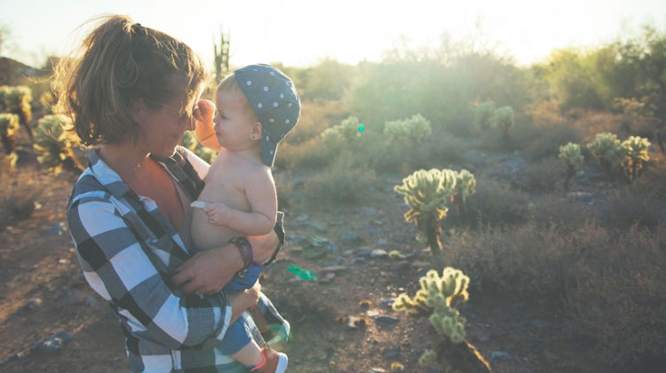 mom holding little boy with hat in desert