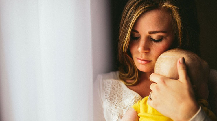 solemn mother holding baby in yellow