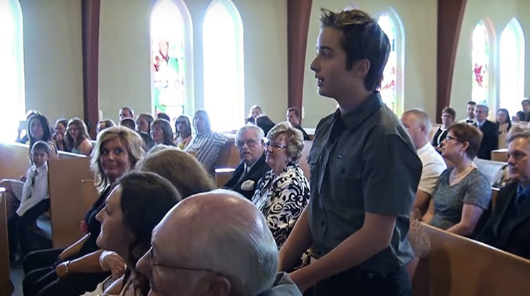 boy stands up in church