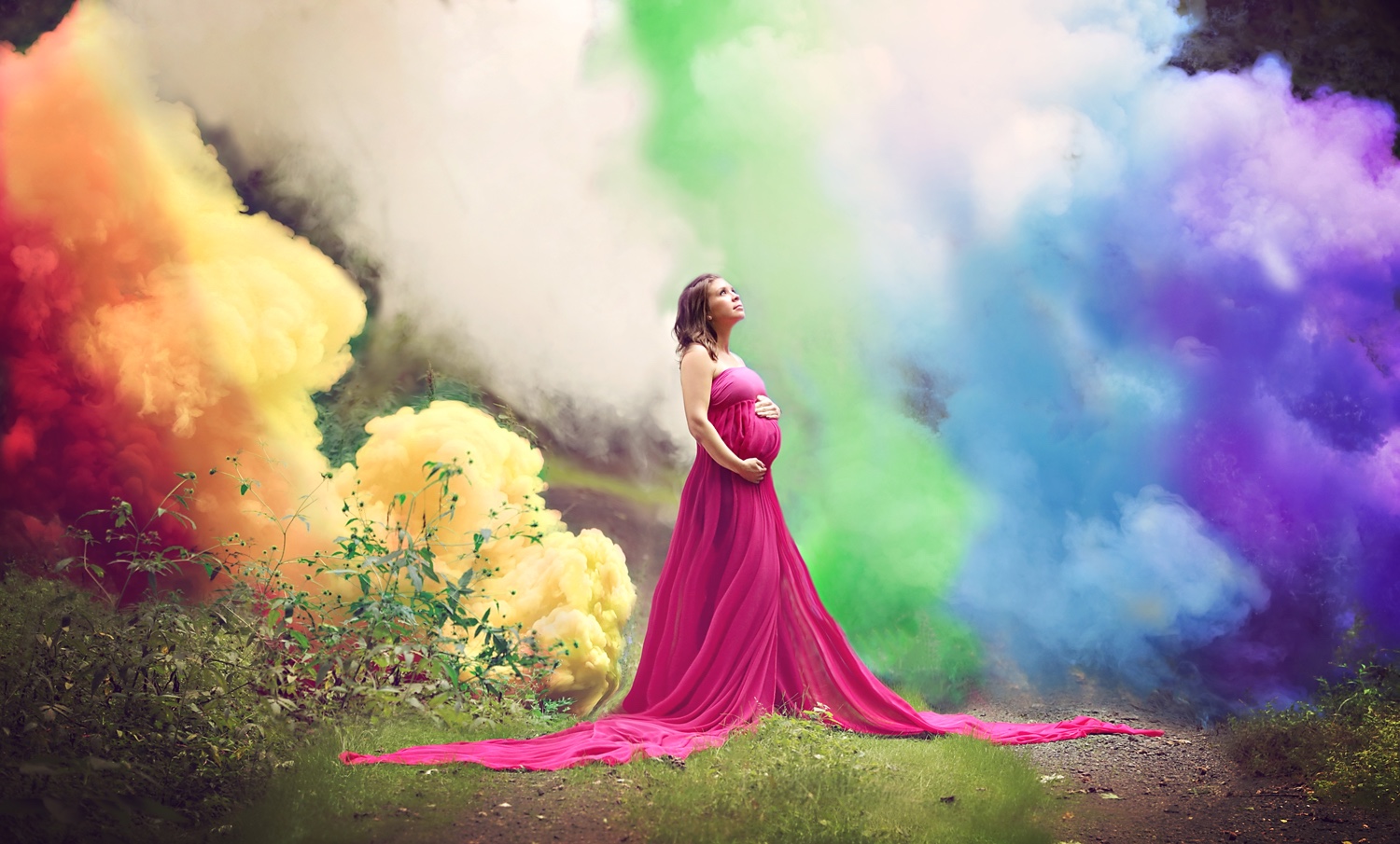 woman in red stands in front of rainbow colored smoke