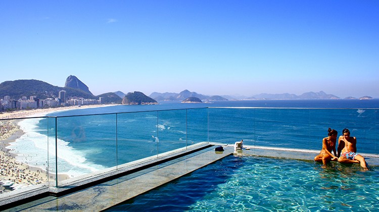 couple sitting on edge of infinity pool above ocean