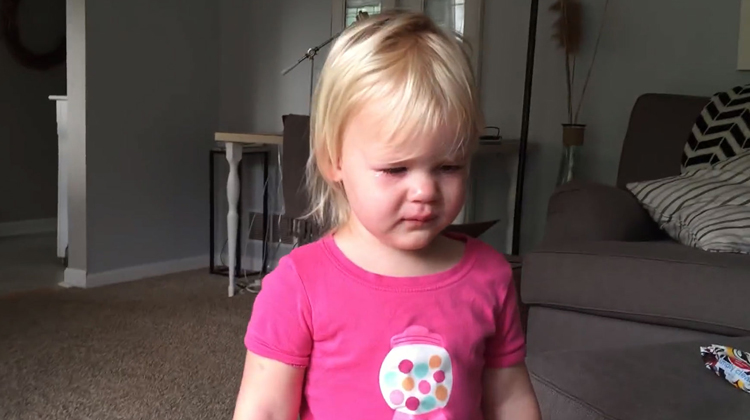 toddler in pink shirt walks in crying