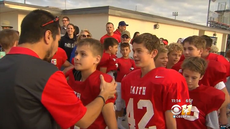 coach holds middle school football players shoulders. line forms behind them
