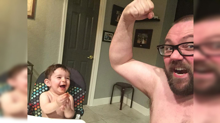 son gleeful as dad holds up bicep
