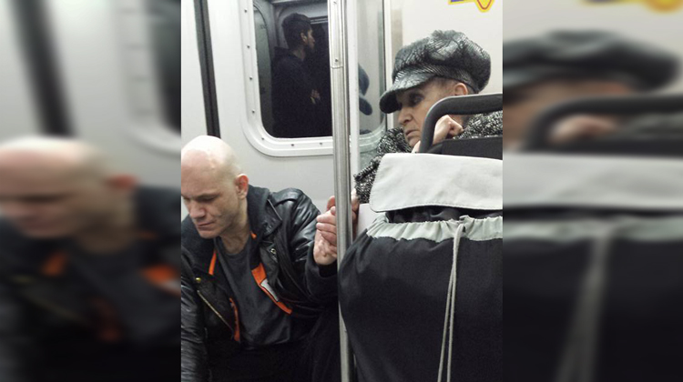 woman on subway holds hand of large man