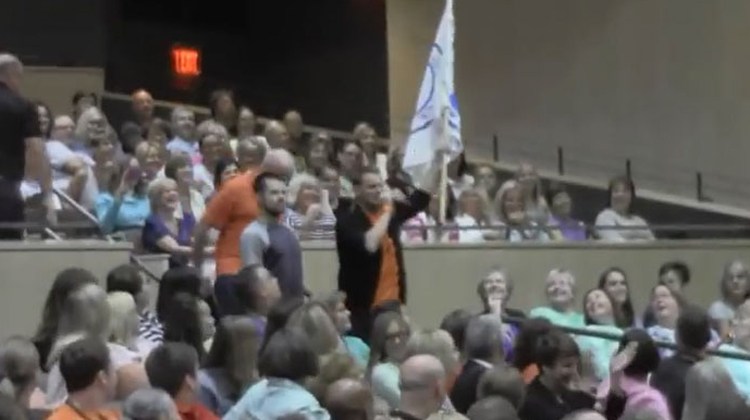 teachers storm stage with flag