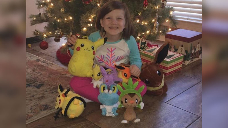 little girl holding pokemon stuffed animals