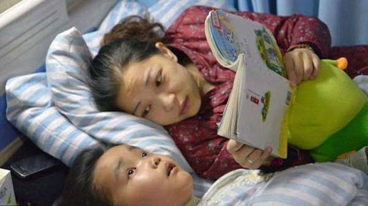 mom in red reads childrens book to son in hospital