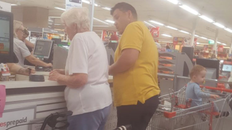 old lady in line, dad in yellow looking at her with baby in cart
